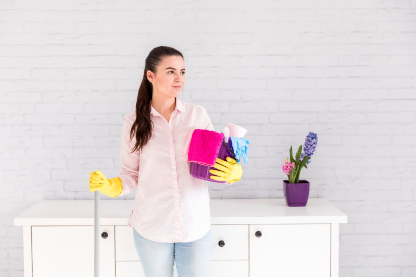 Woman holding cleaning supplies and mop ready to tidy a room quickly