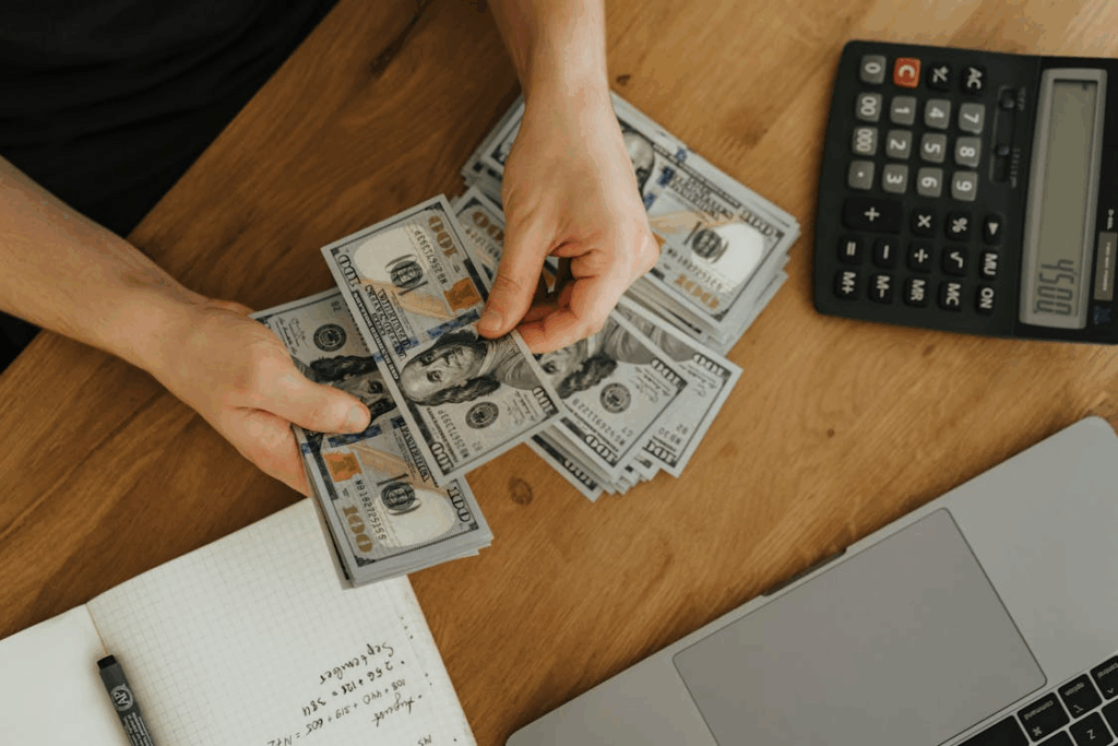 Person counting money with a calculator while planning simple budgeting tips at home.