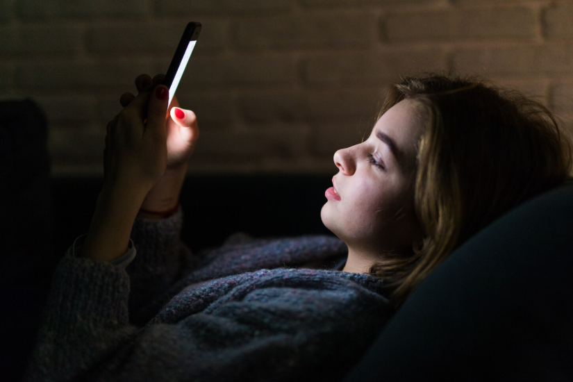 Woman using phone late at night while searching symptoms online.