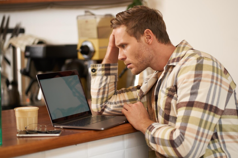 A man looking overwhelmed in front of laptop, searching online for quick relief and clarity.