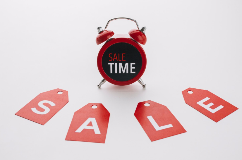 Red alarm clock with “sale time” text surrounded by sale tags symbolizing the best time to buy deals.